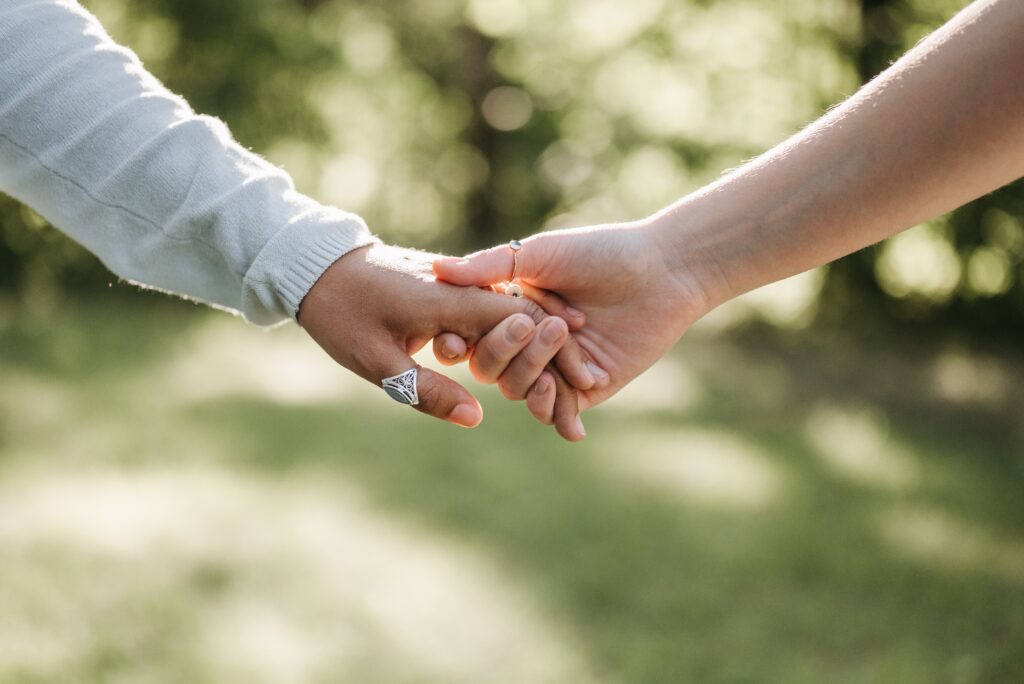 Two people holding hands outside.